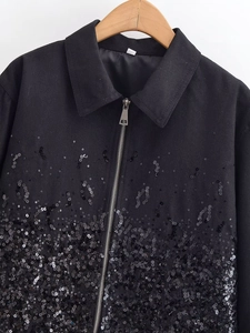 Detail of black sequined jacket showing zip closure and textured twill fabric detail