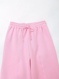 Detail of light pink joggers showing elastic drawstring waistband and vertical seams