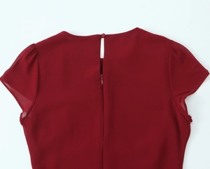 Dettaglio del retro dell'abito rosso scuro con bottone a goccia e cerniera invisibile
