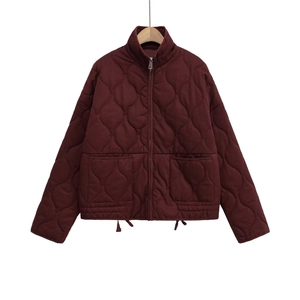 Detail of burgundy quilted jacket featuring stand collar, metal zipper, and large pockets