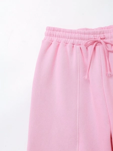 Detail of pink jogging pants featuring elastic drawstring waist and vertical seam stitching