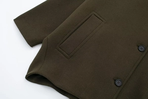 Detail view of olive green wool coat texture with pockets and buttons