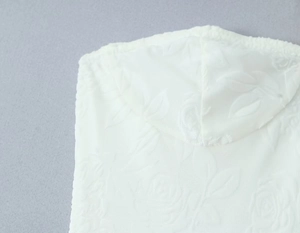 Détail d'une robe blanche avec gaufrage de roses 3D et décolleté à capuche en dentelle
