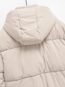 Close-up of the horizontal quilting and hood detail on a beige winter puffer jacket