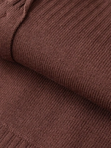 Macro detail of the dark brown knitted texture with fine ribbing and cable patterns