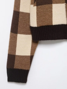 Close-up of brown plaid knit sweater featuring ribbed cuffs and hem with double zipper detail