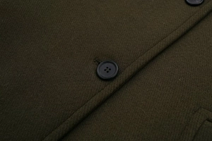 Close-up of olive wool coat with focus on black buttons and precision stitching details