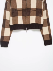 Detail of the brown gingham knit cardigan featuring double zippers and ribbed hem finish