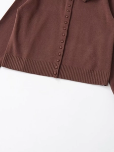 Detail view of brown knit cardigan showing button closure and ribbed hem texture