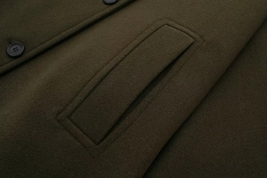 Macro view of wool coat pocket flap and resin button on dark olive green twill fabric