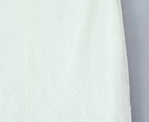 Détail du tissu de robe blanc montrant des motifs jacquard de roses en relief