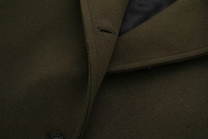 Detailed macro view of olive green wool coat fabric texture and buttonhole stitching