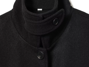 Detailed view of black wool jacket featuring a stand collar and buttoned neck strap