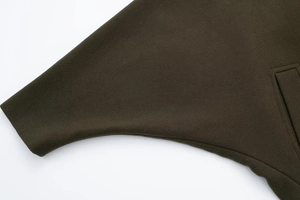 Detailed close-up of dark olive green wool coat fabric texture and professional stitching