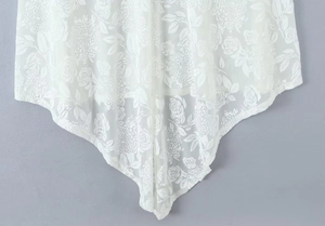 Détail de l'ourlet en dentelle blanche avec motifs floraux et coupe asymétrique