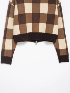 Detail of brown and beige checkerboard knit sweater with textured fabric and metal zipper