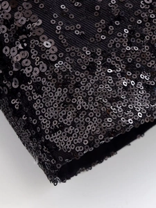 Macro shot of black sequined fabric detailing on the winter jacket sleeve and cuff