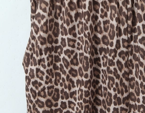 Detailed close-up of leopard print fabric with side pocket stitching and smooth texture