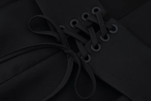 Detailed macro view of black lace-up corset design with metallic eyelets and ribbon bow
