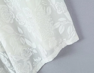 Vue macro d'un tissu blanc transparent avec broderie jacquard de roses en 3D détaillée