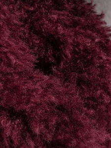 Close-up of fluffy burgundy faux fur fabric with premium long-fiber texture and soft touch