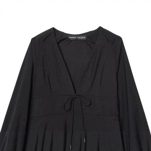 Elegante zwarte jurk met V-hals en lange mouwen met strikceintuur in gladde satijnstof