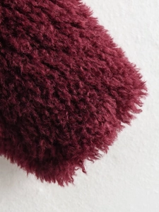 Close-up detail of luxurious wine red faux fur fabric with dense and fluffy texture
