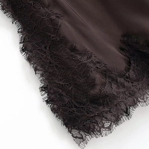 Macro shot of eyelash lace trim detail on a dark coffee-colored silk slip dress