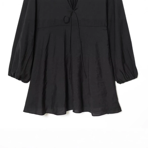 Elegante zwarte jurk met V-hals, strikdetail en lange lantaarnmouwen