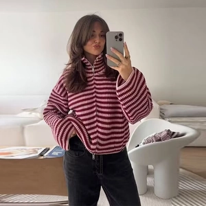 Détail d'un pull en maille rayé bordeaux et rose avec un col zippé réglable argenté