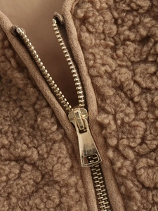 Detailed macro view of the premium gold zipper and soft brown fleece texture on a jacket