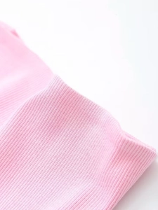 Detailed macro shot of light pink ribbed knit fabric texture for casual three-piece set
