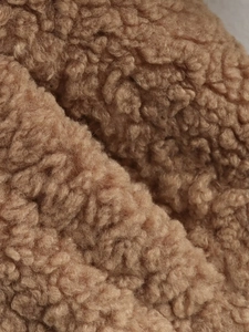 Close-up of soft brown teddy fleece fabric texture with curly wool-like fibers for jackets