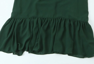 Dettaglio dell'orlo a balze verde scuro con trama in chiffon plissettato