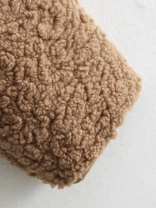 Close-up macro view of high-quality brown sherpa fleece fabric texture on a jacket