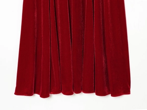 Close-up of red velvet dress hem showing soft texture and elegant pleated details