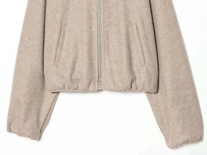 Detail of oatmeal knit jacket showing silver zipper and textured wool blend fabric
