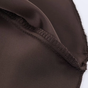 Dettaglio del tessuto satinato marrone scuro che mostra cuciture overlock di qualità