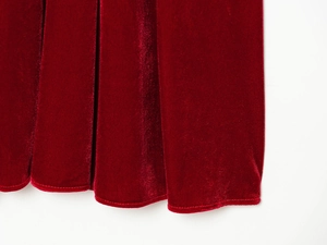 Detailed macro view of deep red velvet fabric with elegant pleats and smooth stitched hem