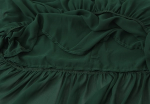 Dettaglio macro dell'abito in chiffon verde scuro con pieghe a strati e fodera interna