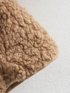 Close-up detail of brown sherpa fleece texture with reinforced stitching on the seam