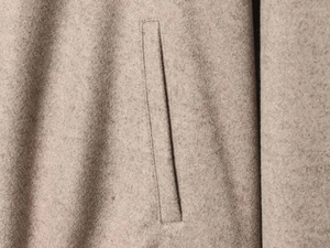 Detail of welt pocket on dark beige wool-textured slim jacket with dense felted fabric