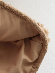 Macro detail of the plush fleece texture and inner lining of the brown zip-up jacket