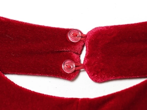 Detail of red velvet dress featuring back closure with double clear resin buttons
