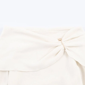Macro view of cream knit fabric texture with an elegant gold bead embellishment