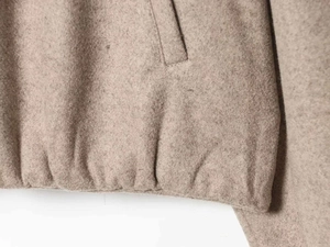 Detailed close-up of wool-blend fabric texture with pocket and elastic hemline