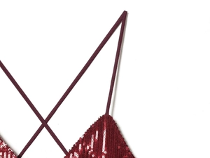 Detail of burgundy sequin dress showing delicate cross straps and shimmering texture
