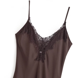 Macro detail of the deep V-neckline with delicate black eyelash lace on a brown satin dress