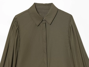 Detail of dark olive green poplin shirt featuring pleated shoulders and pointed collar