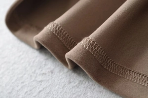 Detailed macro shot of brown suede fabric showing fine texture and quality overlock stitching